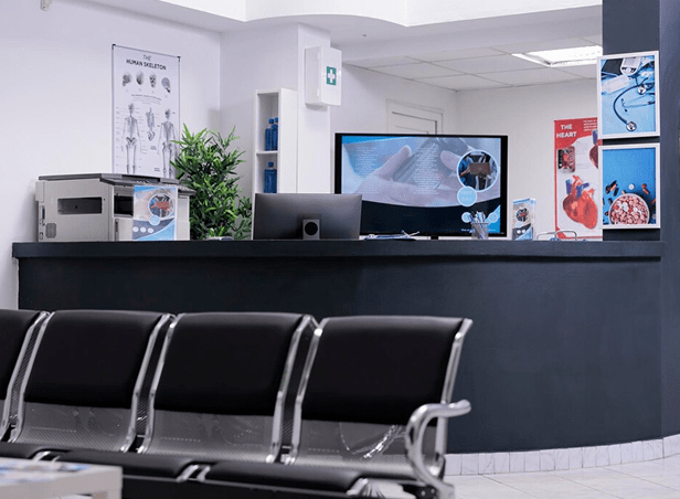 Healthcare clinic reception area with waiting room chairs and check-in desk.